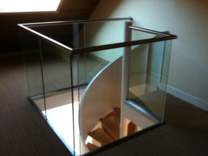 ecalier colimaçon avec un garde corps en verre et une main courante inox